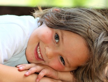 A child lying on the floor, awake and smiling, but resting