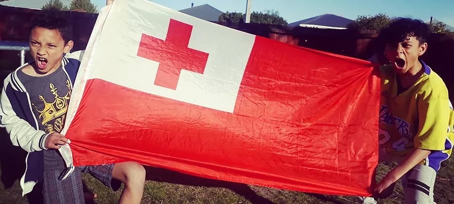 Two of the Loopy Tunes tamariki holding out a Tongan flag