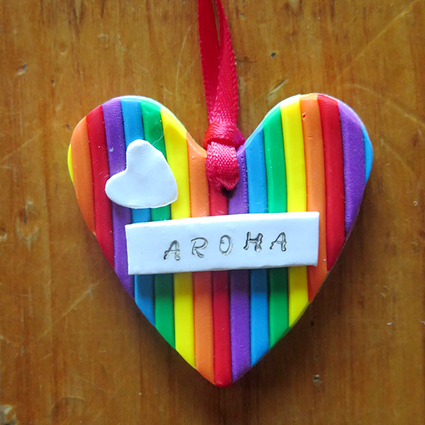 Christmas tree decoration, a heart made with rainbow colours, and the word 'Aroha' on the front